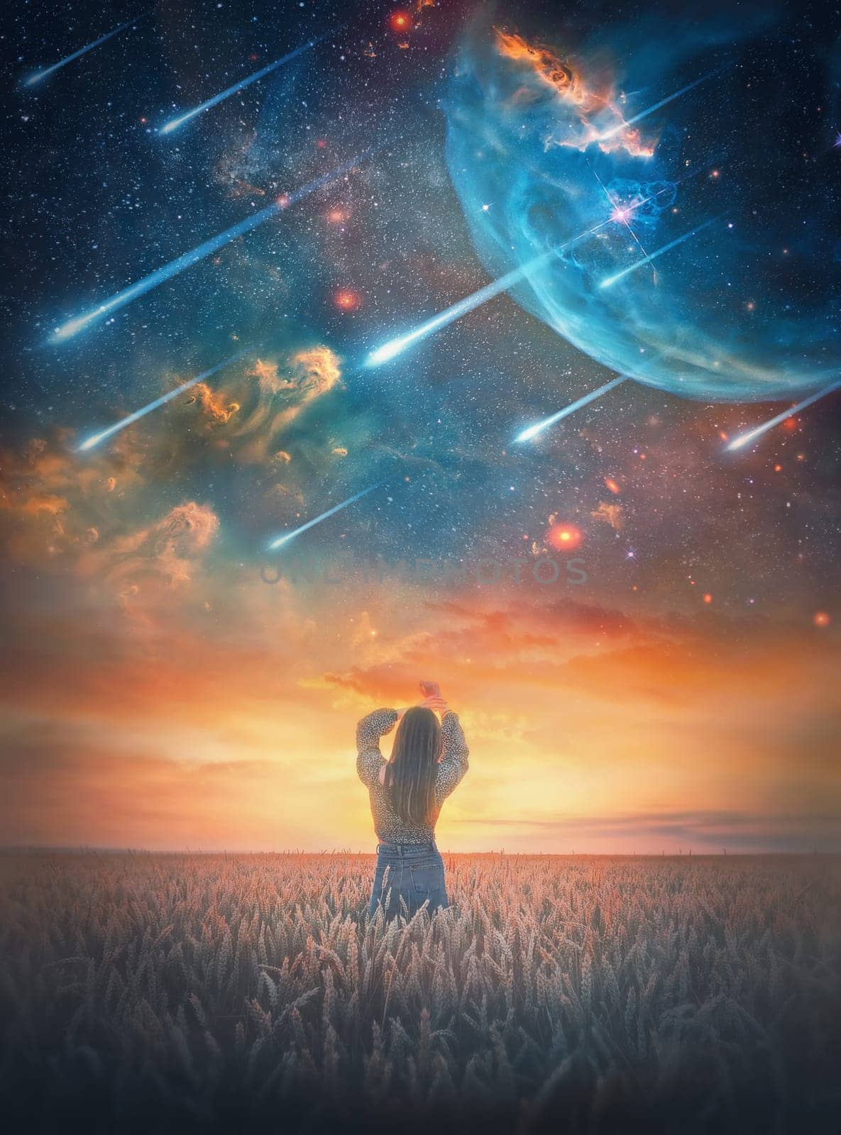 Carefree young woman in the wheat field facing the magical cosmic phenomenon. Wild and free girl rear view portrait at twilight under the starry sky falling comets. Fantastic space scenery