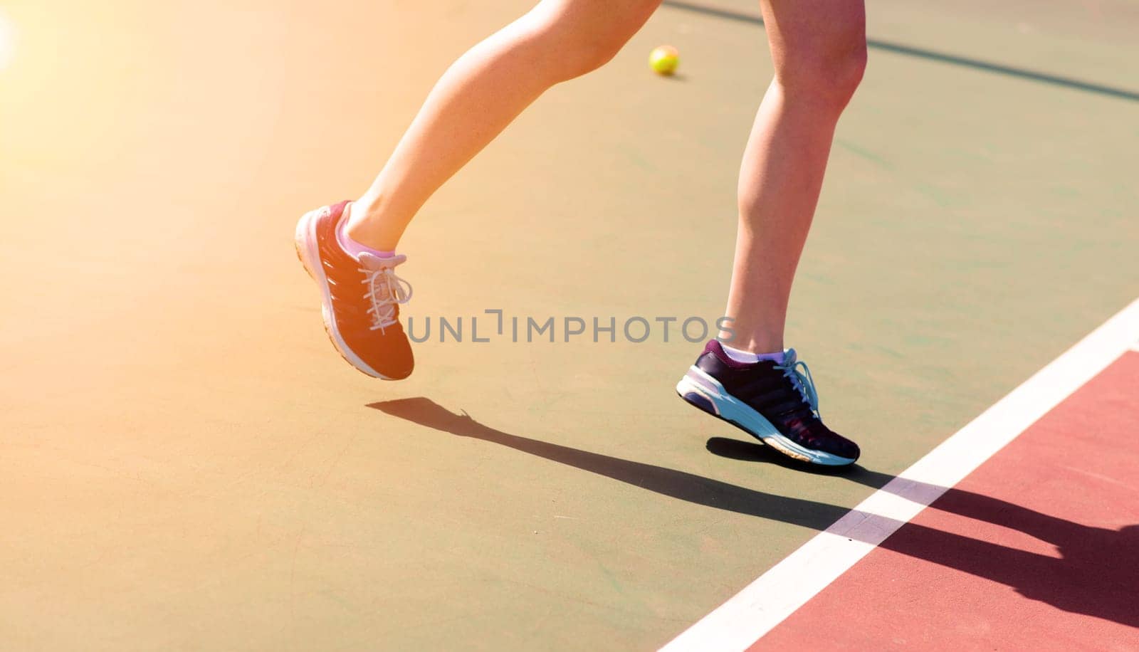 Legs of young girl in a closed tennis court with racket