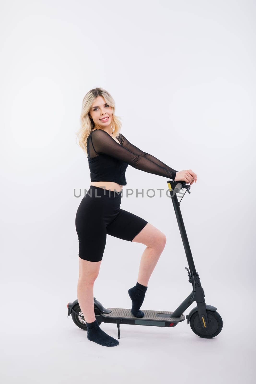 Blonde woman on a red and white background sit and stand with electro scooter and resting