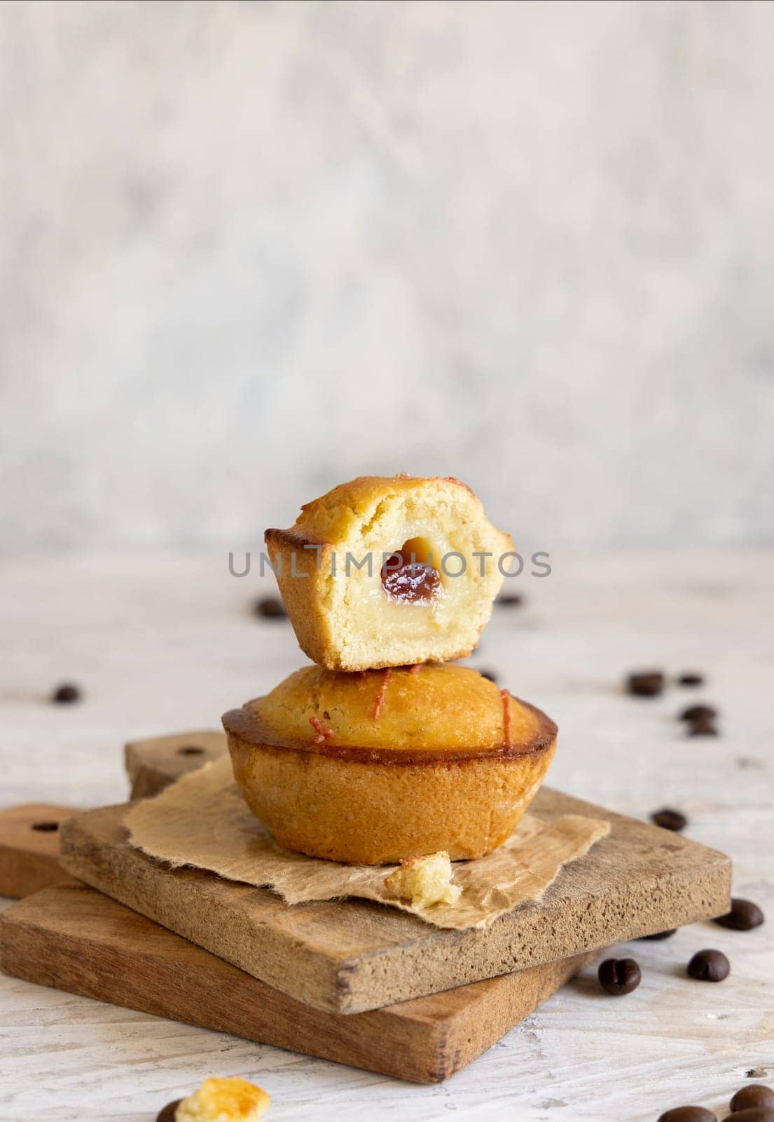Pasticciotto leccese pastry filled with egg custard cream and sour cherry jam. Pieces of pasticiotto on a wooden board, typical apulian breakfast, close up, copy space. Table decorated with coffee beans