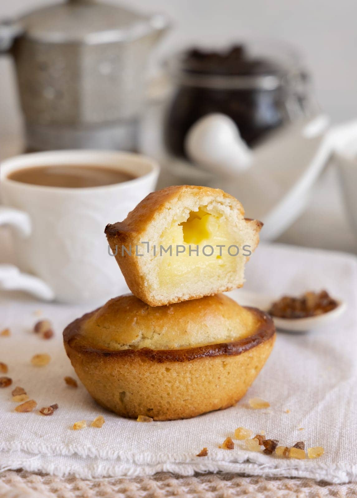 Pasticciotto leccese pastry filled with egg custard cream, typical sweet from Lecce, Italy. Pieces of pasticiotto on a beige napkin, apulian breakfast with coffee prepared, close up