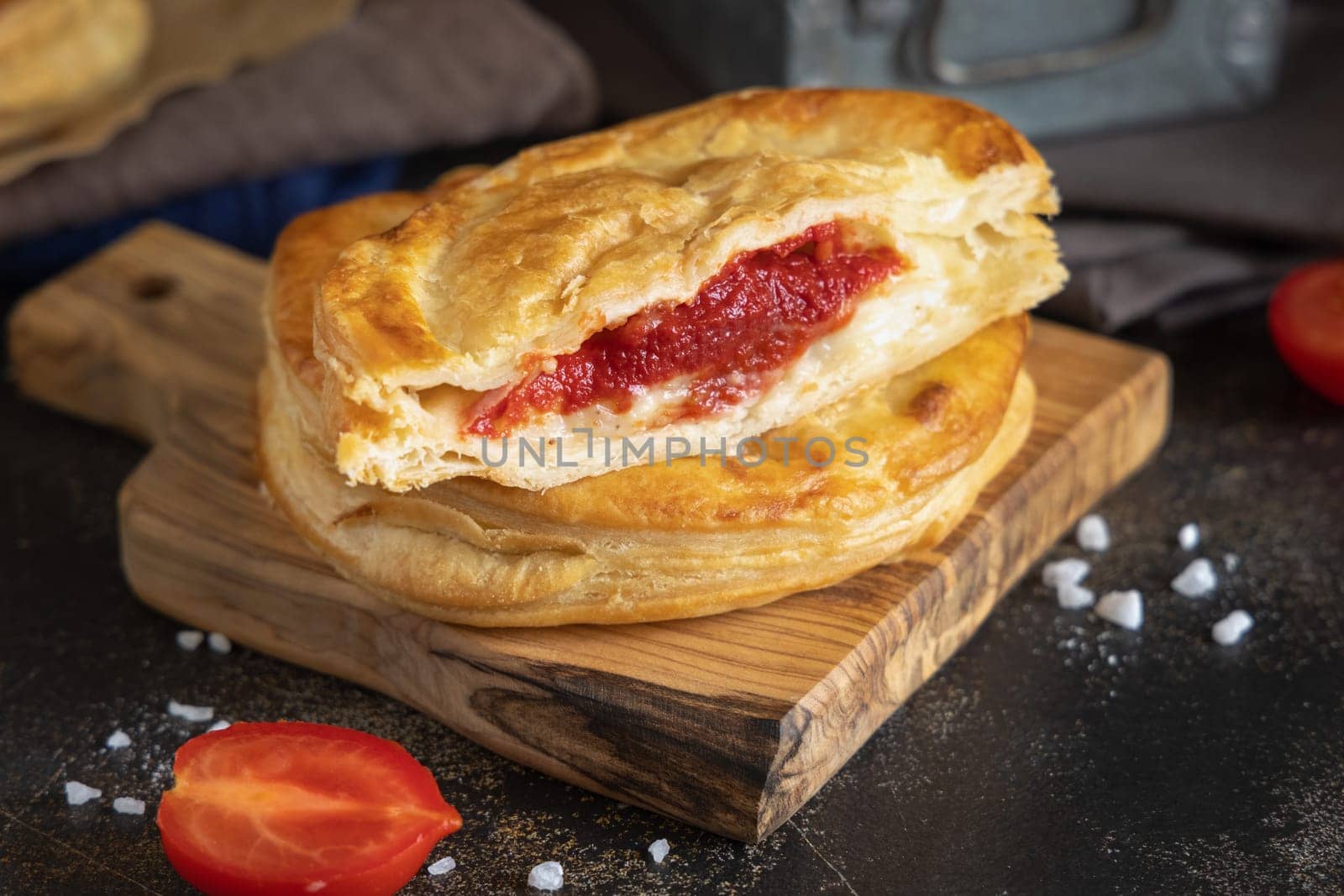 Rustico traditional puff pastry stuffed with bechamel sauce, tomato and mozzarella cheese, close up on a dark table. Traditional street food from Salento, Lecce, Italy