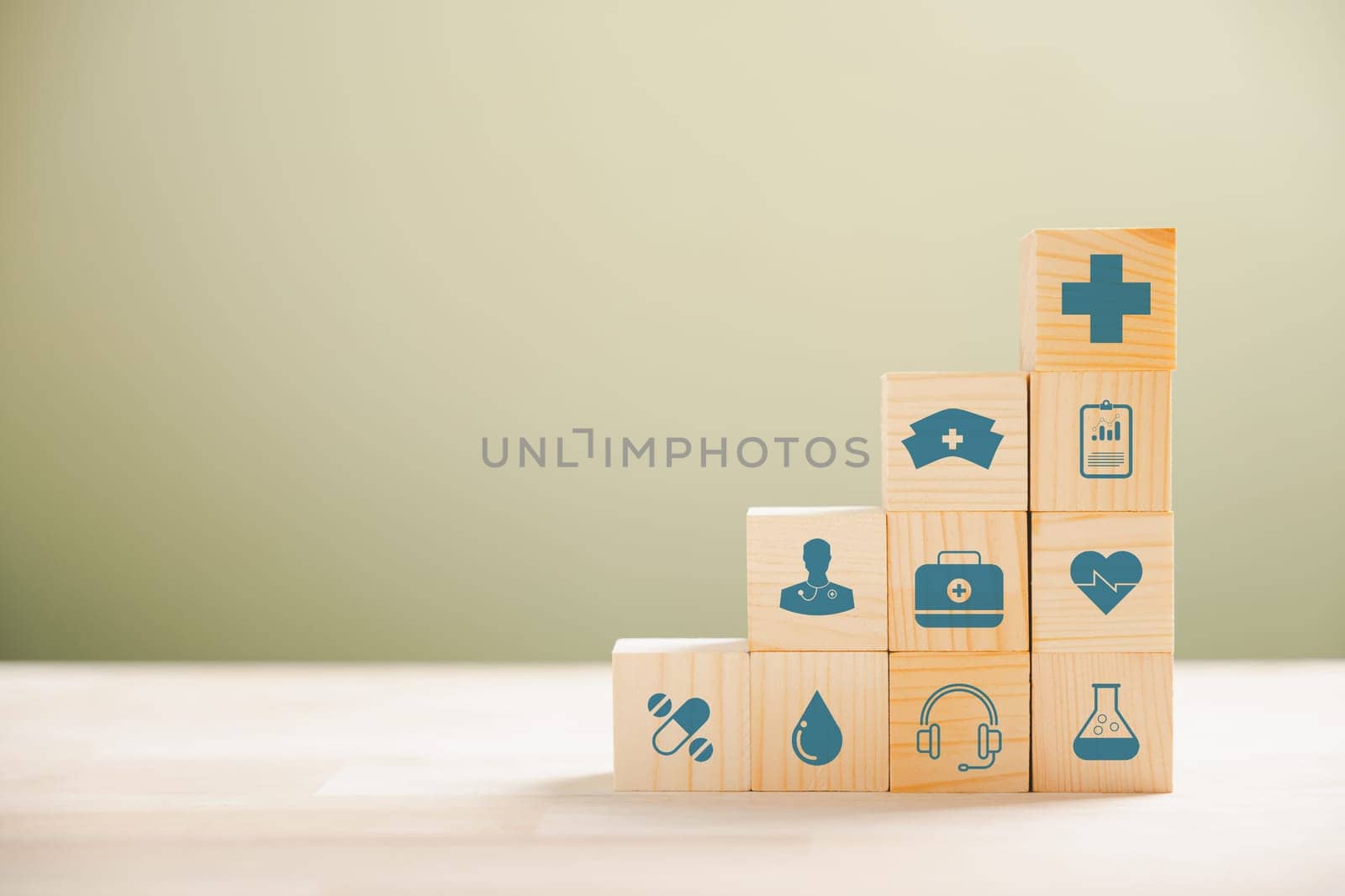 Pyramid of wooden cubes signifies healthcare and insurance commitment. Top medical insurance icon represents safety. Blue background accommodates copyspace for Health Insurance idea.