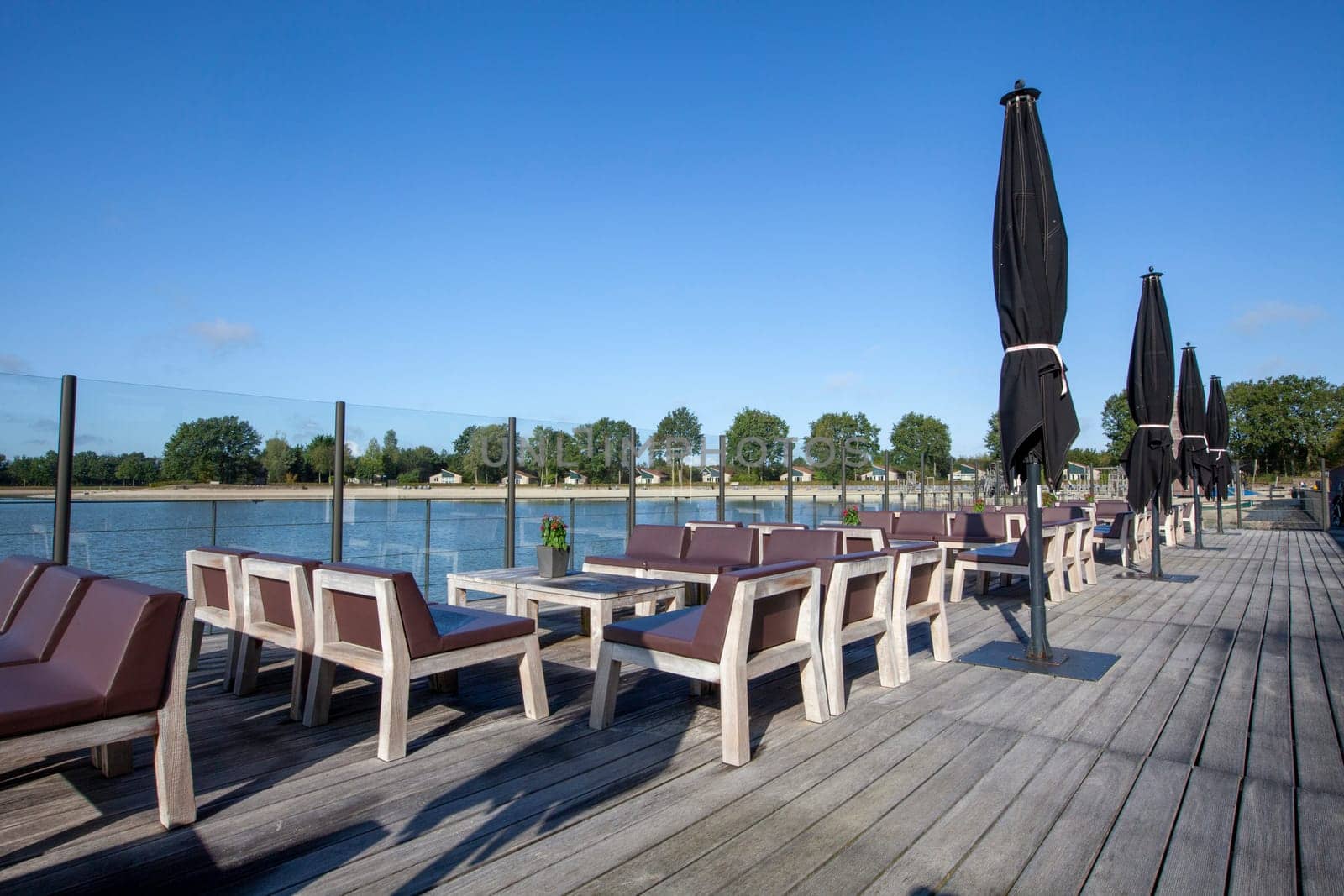 beach chair and black umbrella on the floor with lake view and a blue sky