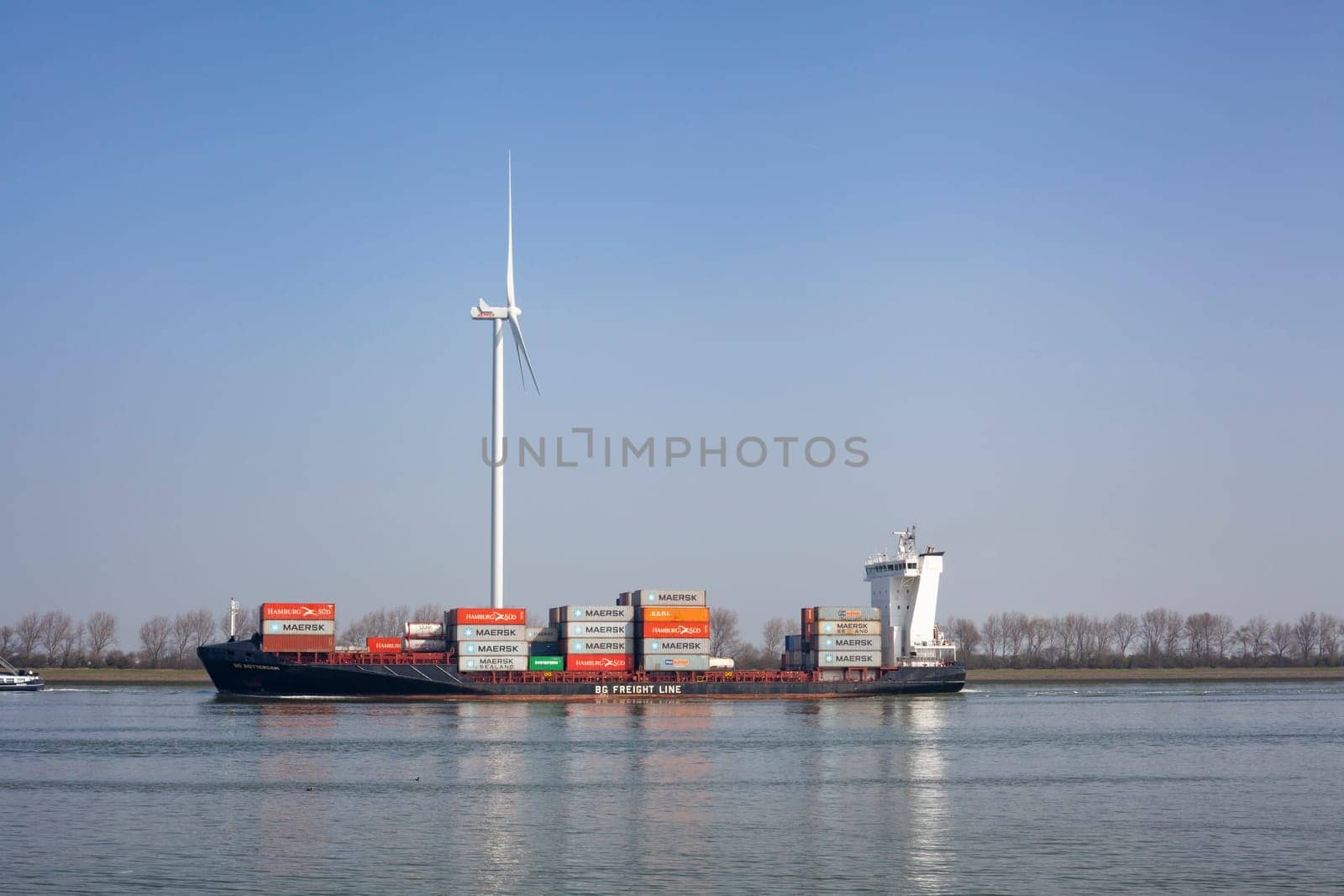 Netherlands, New Waterway. Container ship in front of modern windmill shipping, transport and heavy industry nera Maasvlakte 2.