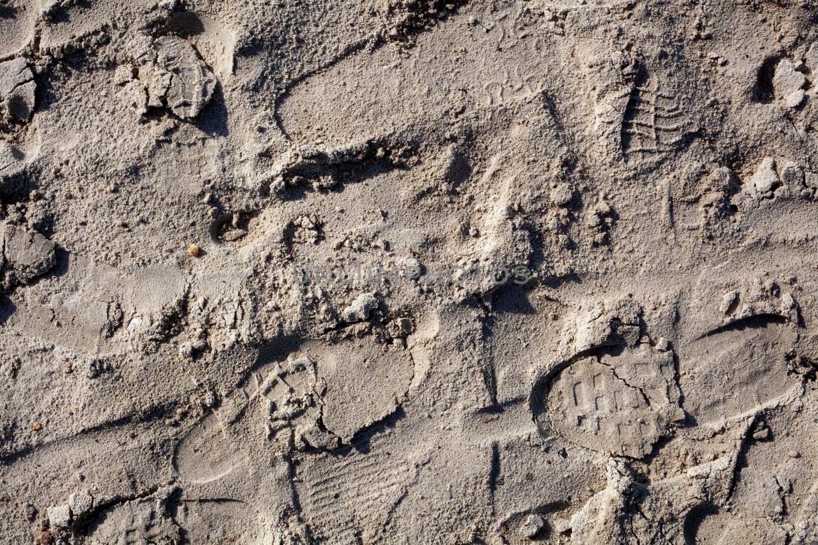 Many different footprints on yellow sand at summer sunny day
