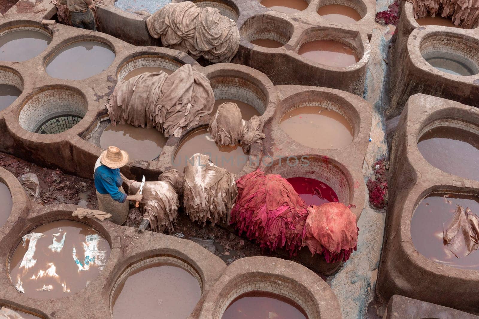 Man working in Tanneries of Fes. Old tanks with color paint for leather. Morocco Africa