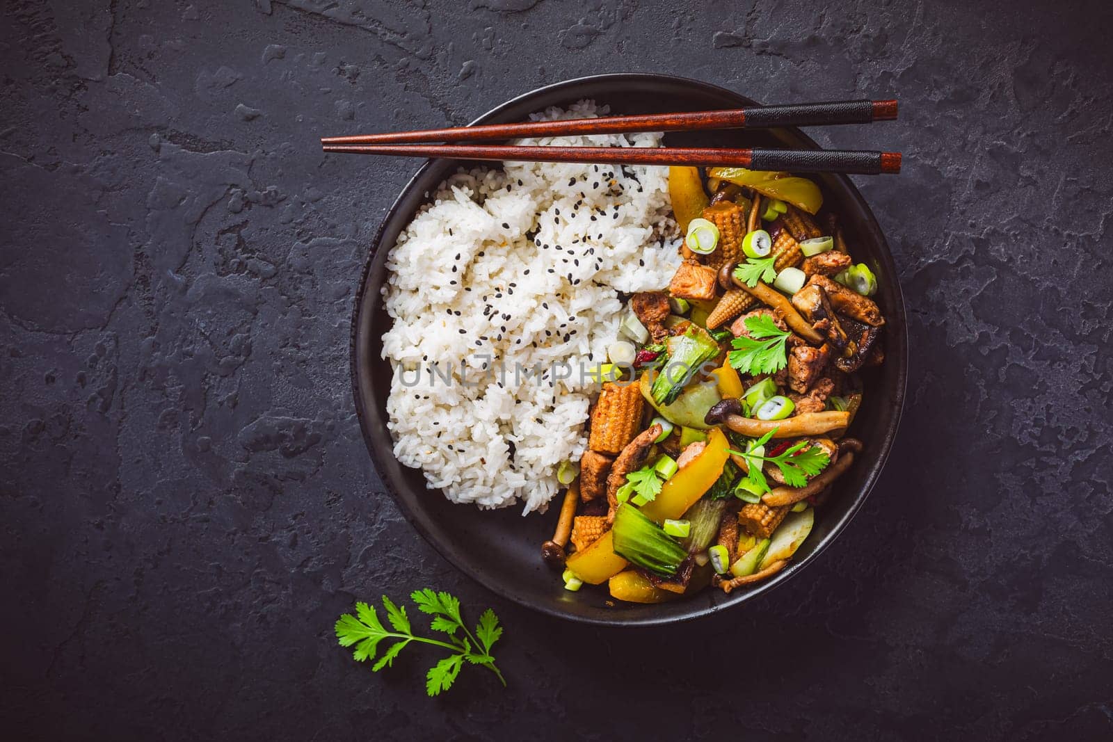 Stir-fry with mushrooms, vegetables and rice on dark background. Asian style food