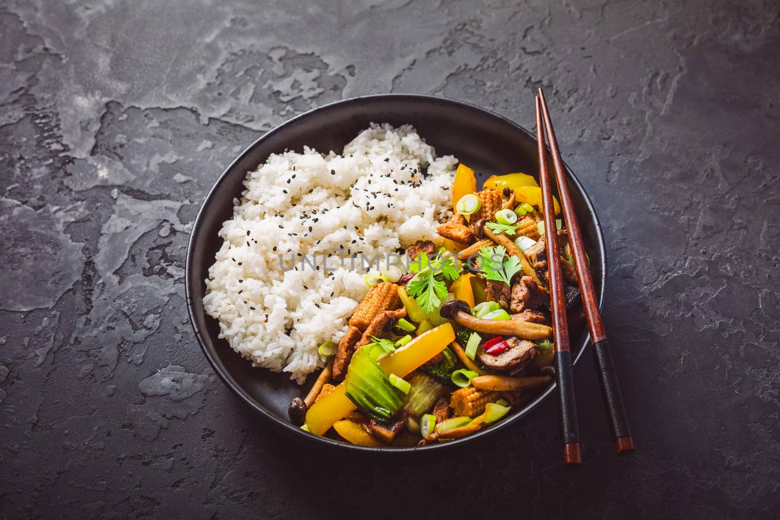 Stir-fry with mushrooms, vegetables and rice on dark background. Asian style food