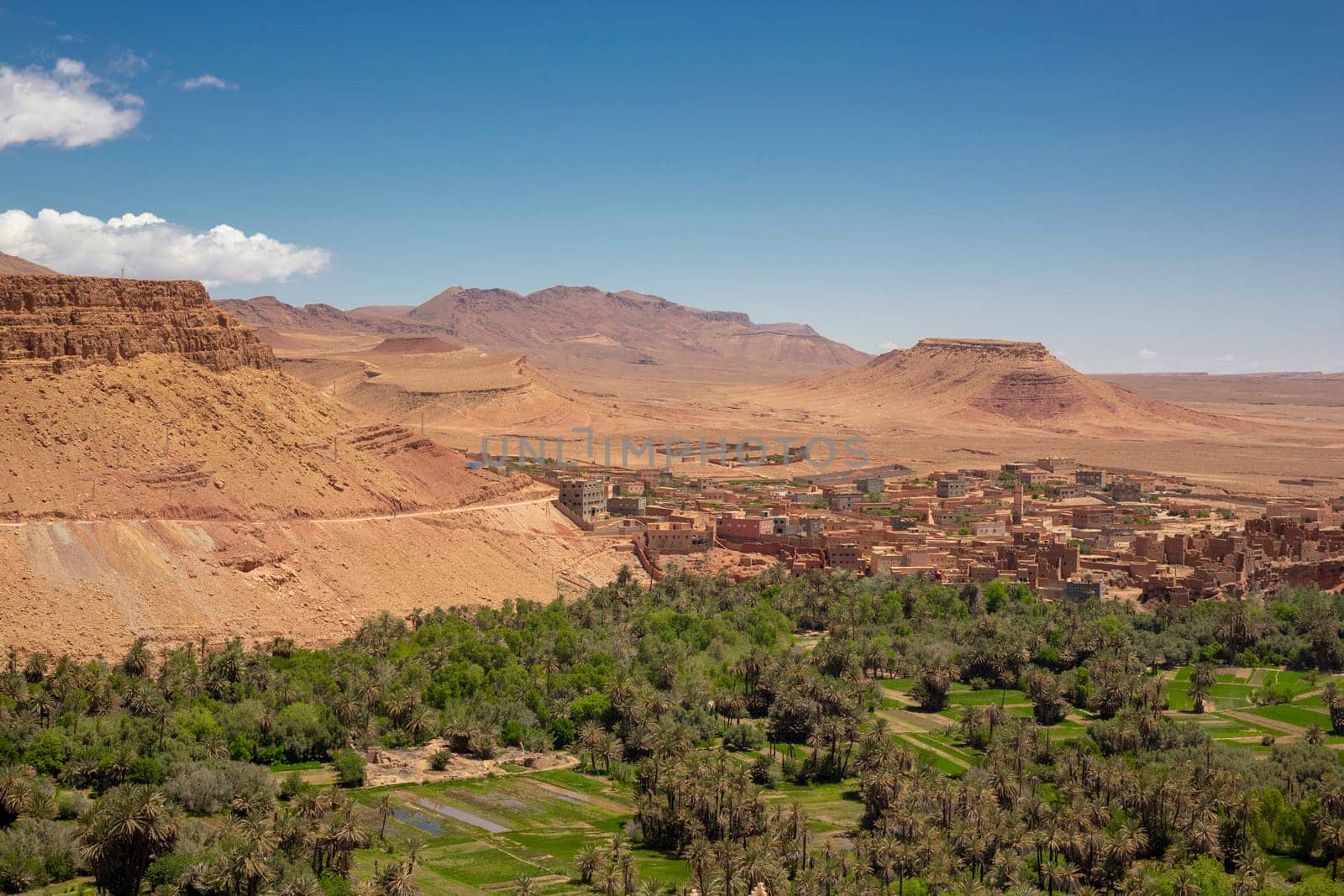 Old town of Tinghir, green palm oasis and rocky Atlas Mountains range landscape in southeastern Morocco with clear blue sky, Africa