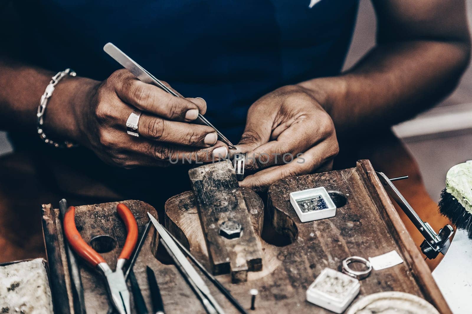 Jeweler making handmade jewelry on vintage workbench. Craft of jewelery making. Repairing ring by inlaid tight gem.