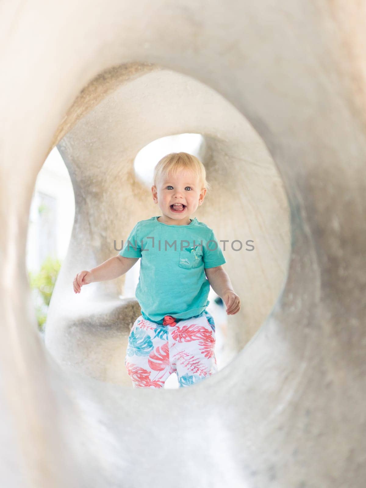 Child playing on outdoor playground. Toddler plays on school or kindergarten yard. Active kid on stone sculpured slide. Healthy summer activity for children. Little boy climbing outdoors