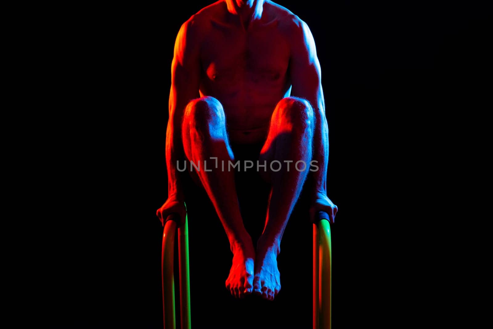 Front and side view photo of strong young man exercising on parallel bars in studio.