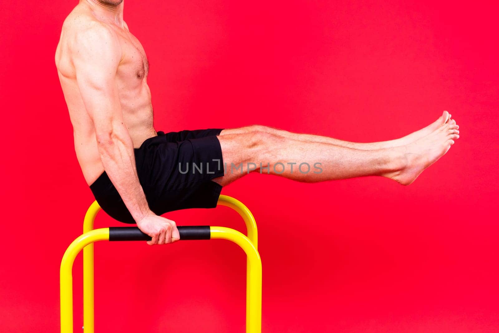 Front and side view photo of strong young man exercising on parallel bars in studio.