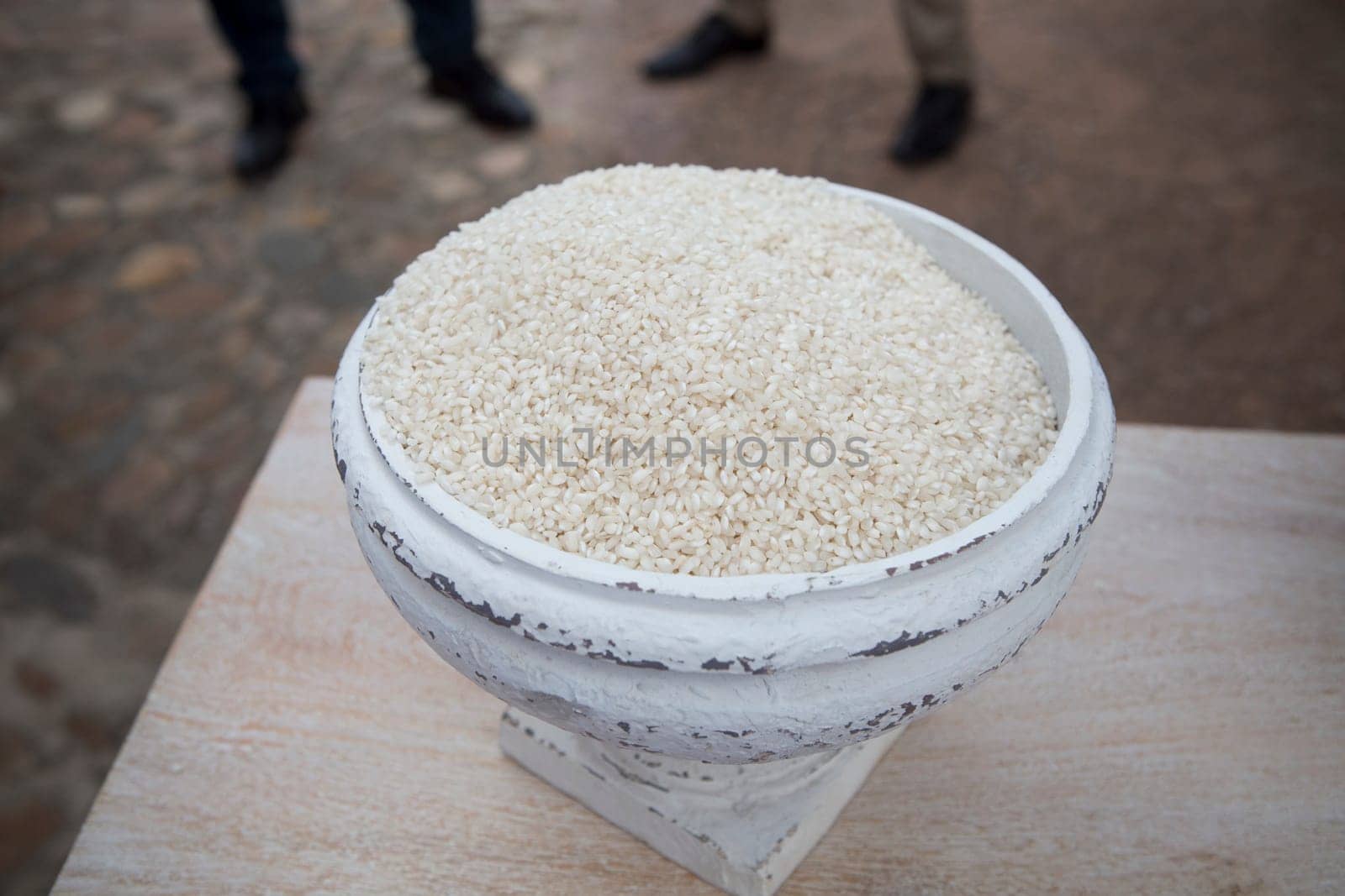 Greek vase with rice for wedding. Guest legs as background