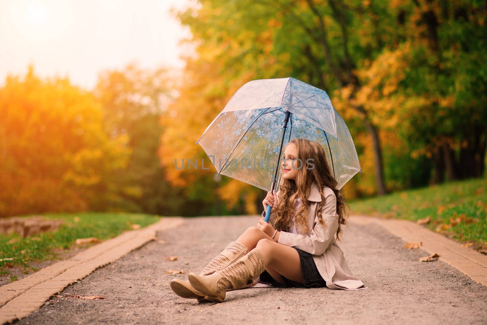 Young attractive smiling girl under umbrella in an autumn forest