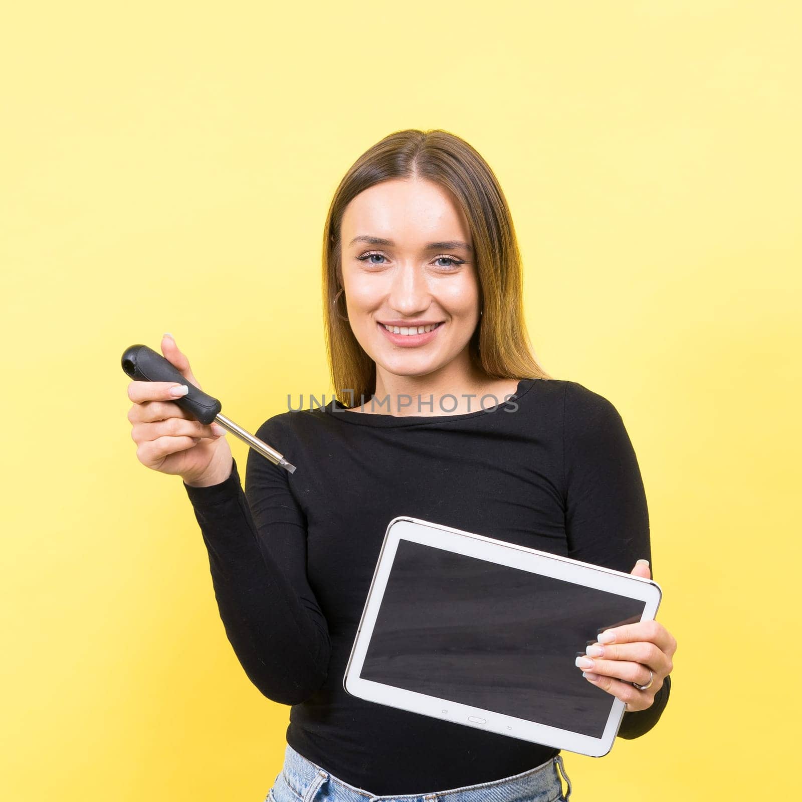 Service center. Laptop Repair. Female screwdriver unscrews laptop bolts on a yellow background