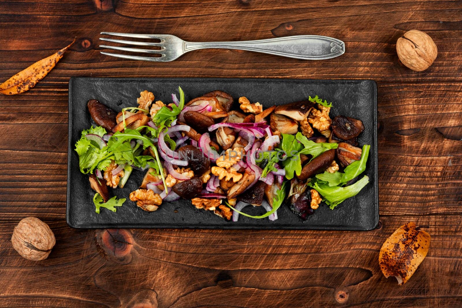 Diet salad with grilled forest mushrooms, onions, green and walnuts. Top view, copy space.