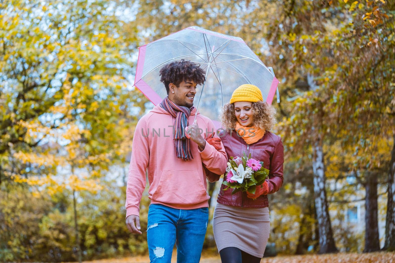 Couple with different ethnicities having a autumn walk in the park full of fall colors
