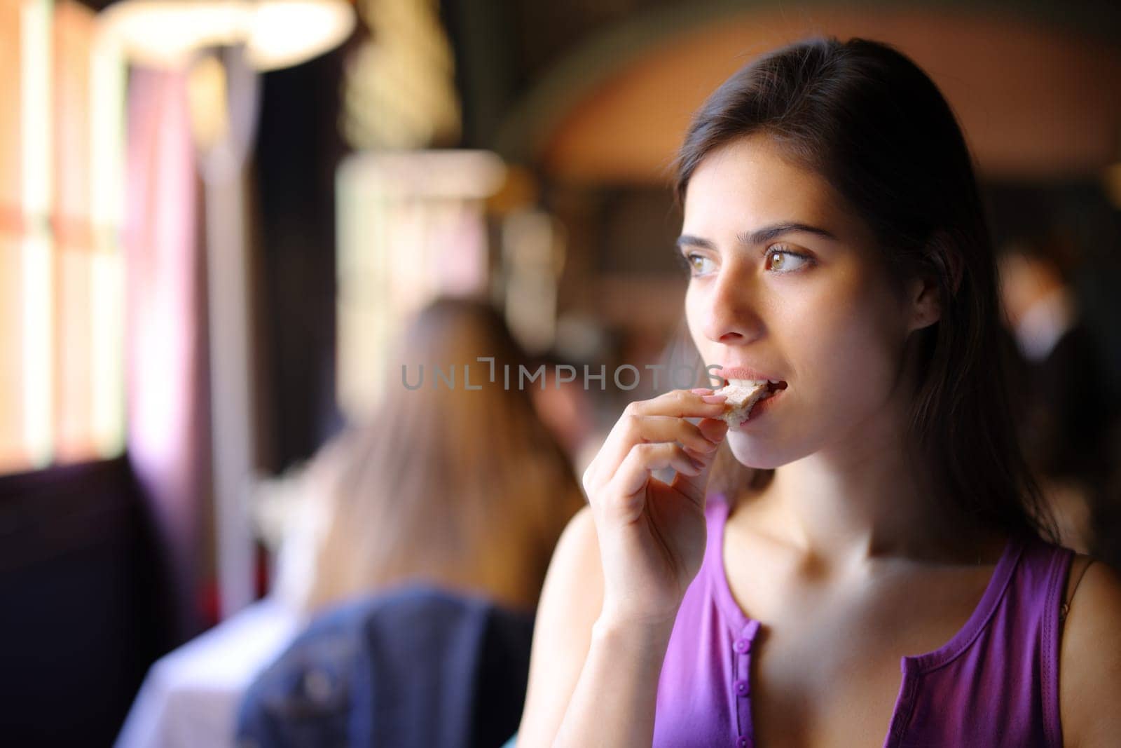 Beautiful customer eating bread in a restaurant interior