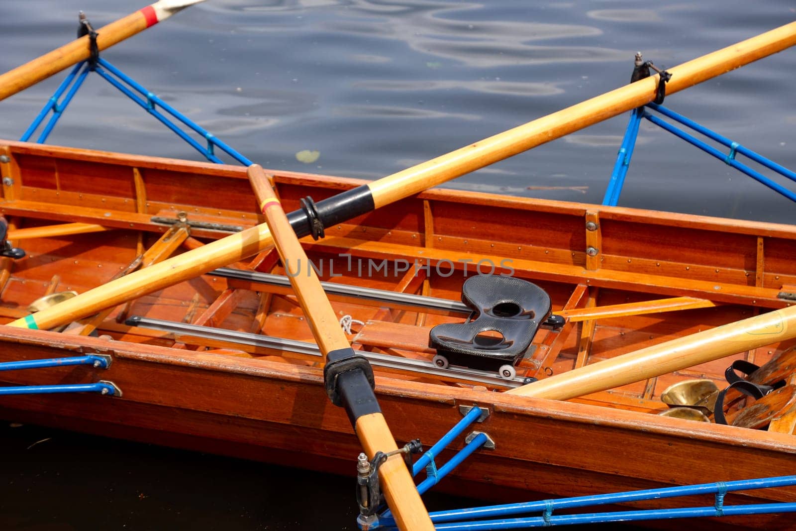A rowing boat, multi-seater has moored to a jetty at a boathouse.