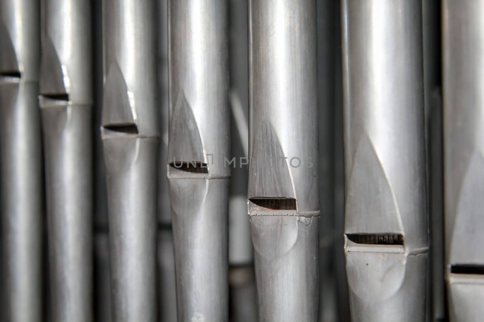 Many organ pipes stand side by side in an organ over a bellows.
