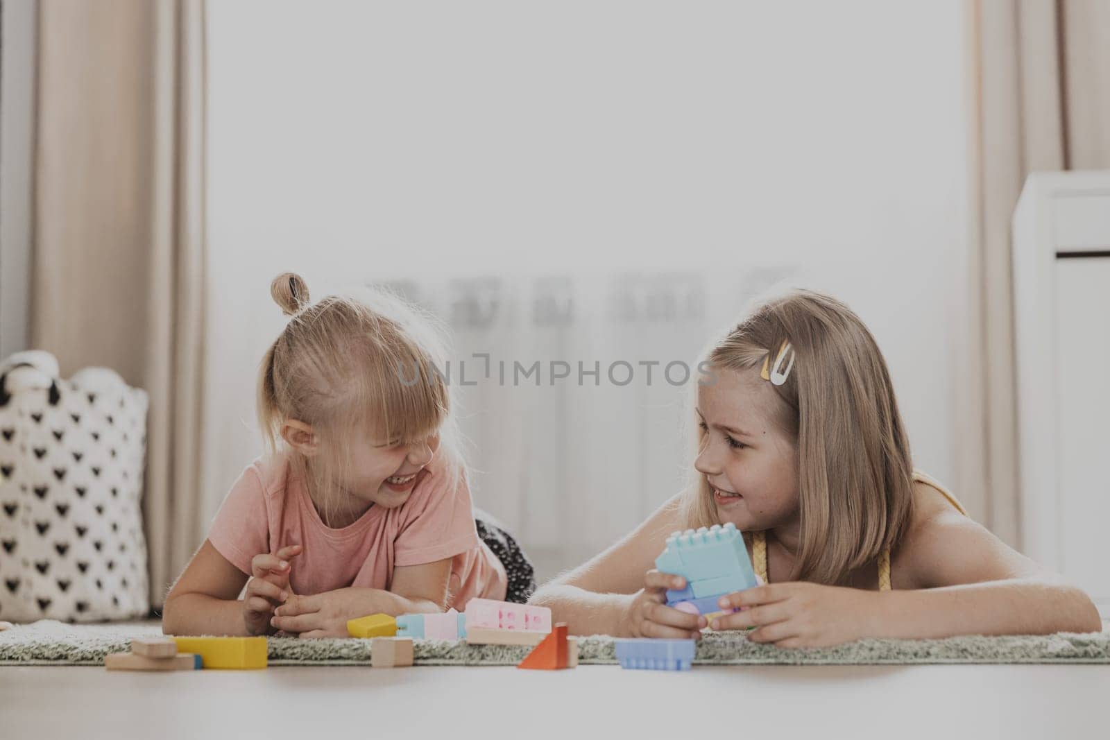 Children playing with colorful toys. Kids sitting on carpet at home bedroom or kindergarten. Development of fine motor skills, imagination, logical thinking concept. Educational eco-friendly games
