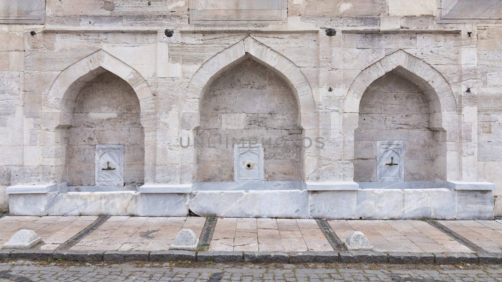 External stone wall of 16th century historic Atik Valide Mosque with row of ablution fountains, located in Uskudar, Istanbul, Turkey, built by Nurbanu Sultan, the mother of Sultan Selim II