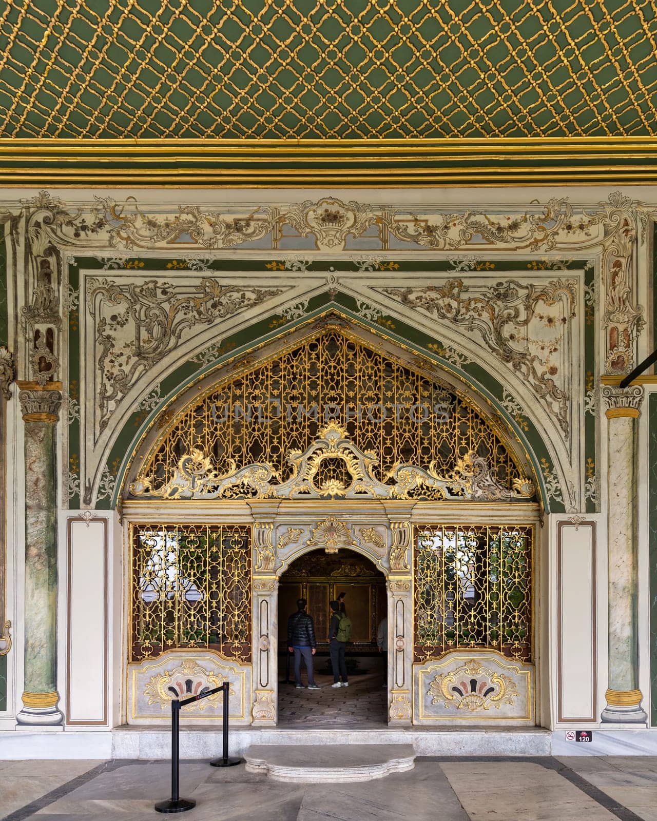Istanbul, Turkey - May 11, 2023: Golden decorated arched entrance in painted ornate wall and green decorated ceiling at the courtyard of Dolmabahce Palace, Besiktas district