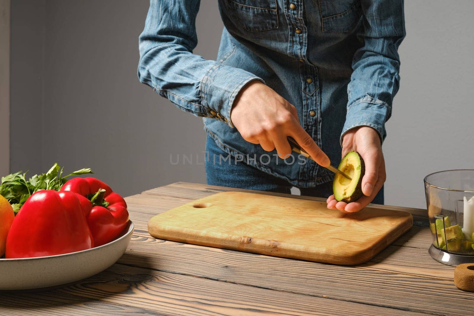 Unrecognizable woman crisscross cutting avocado in the kitchen