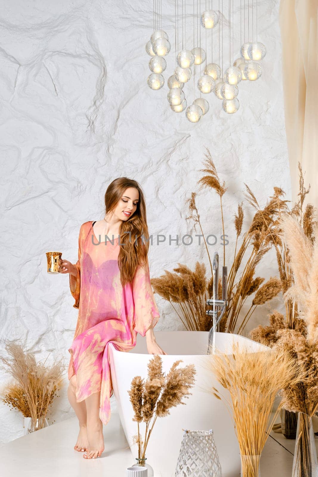 Young sensual woman fills a bath with water for morning relaxation