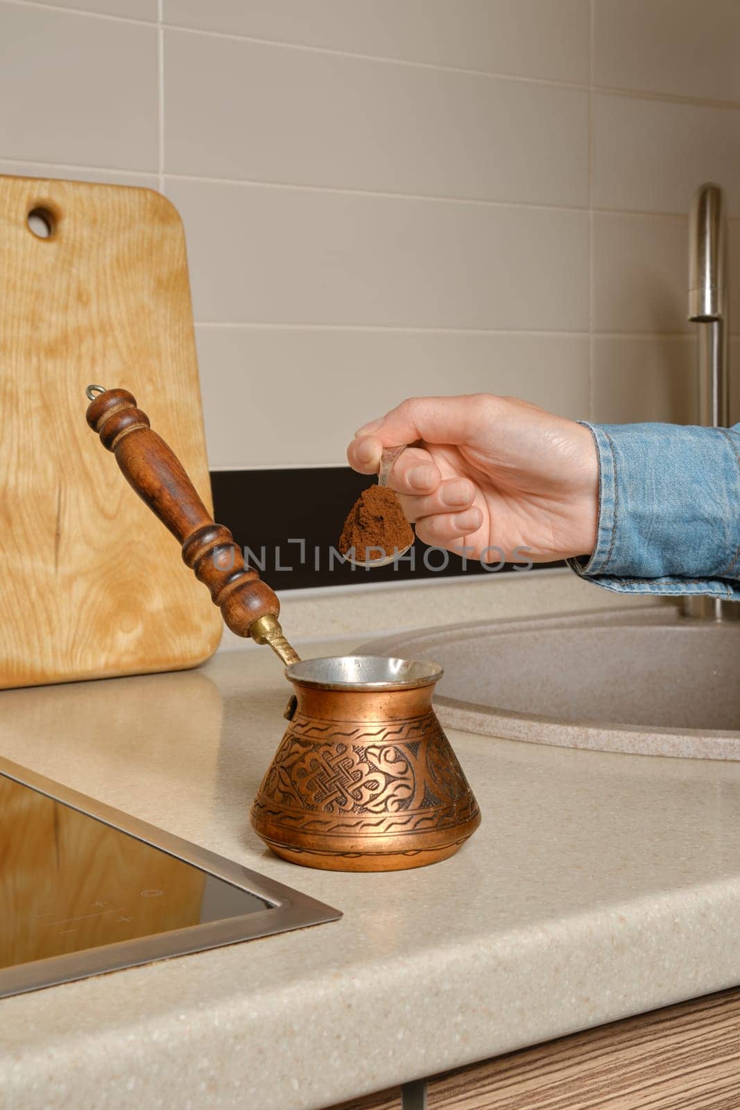 Hand of unrecognizable woman pours ground coffee into a turk