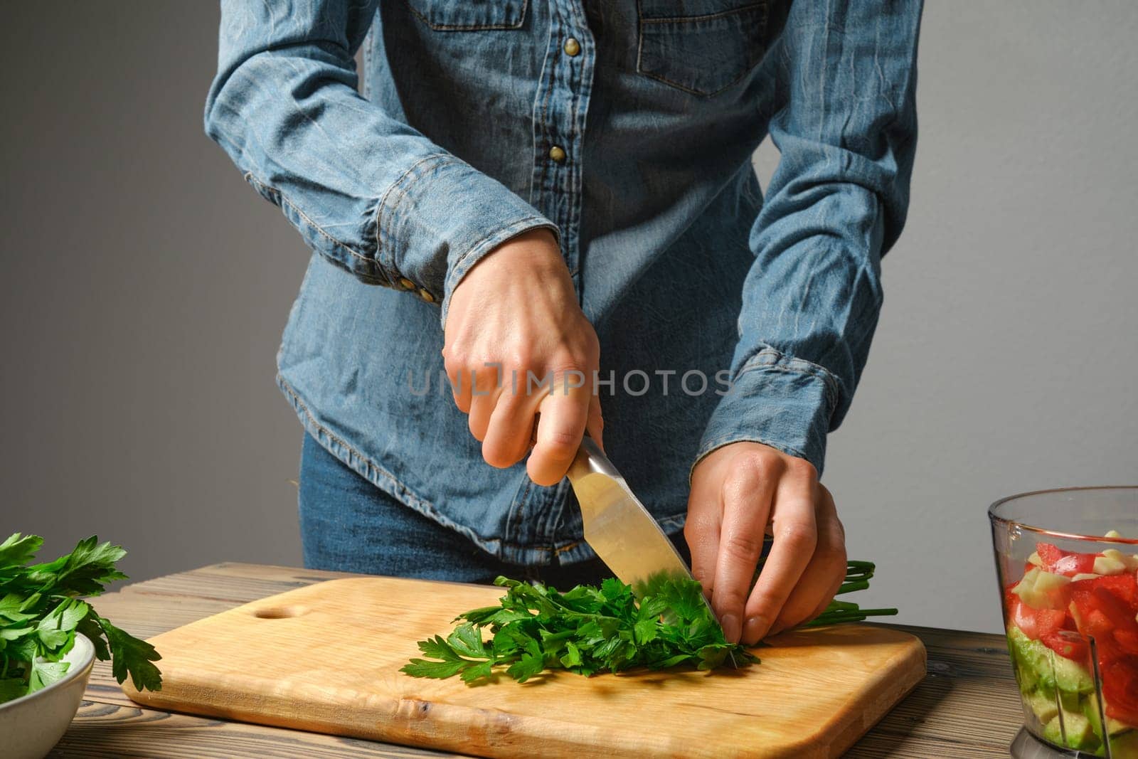 An unrecognizable woman cuts cilantro into large pieces