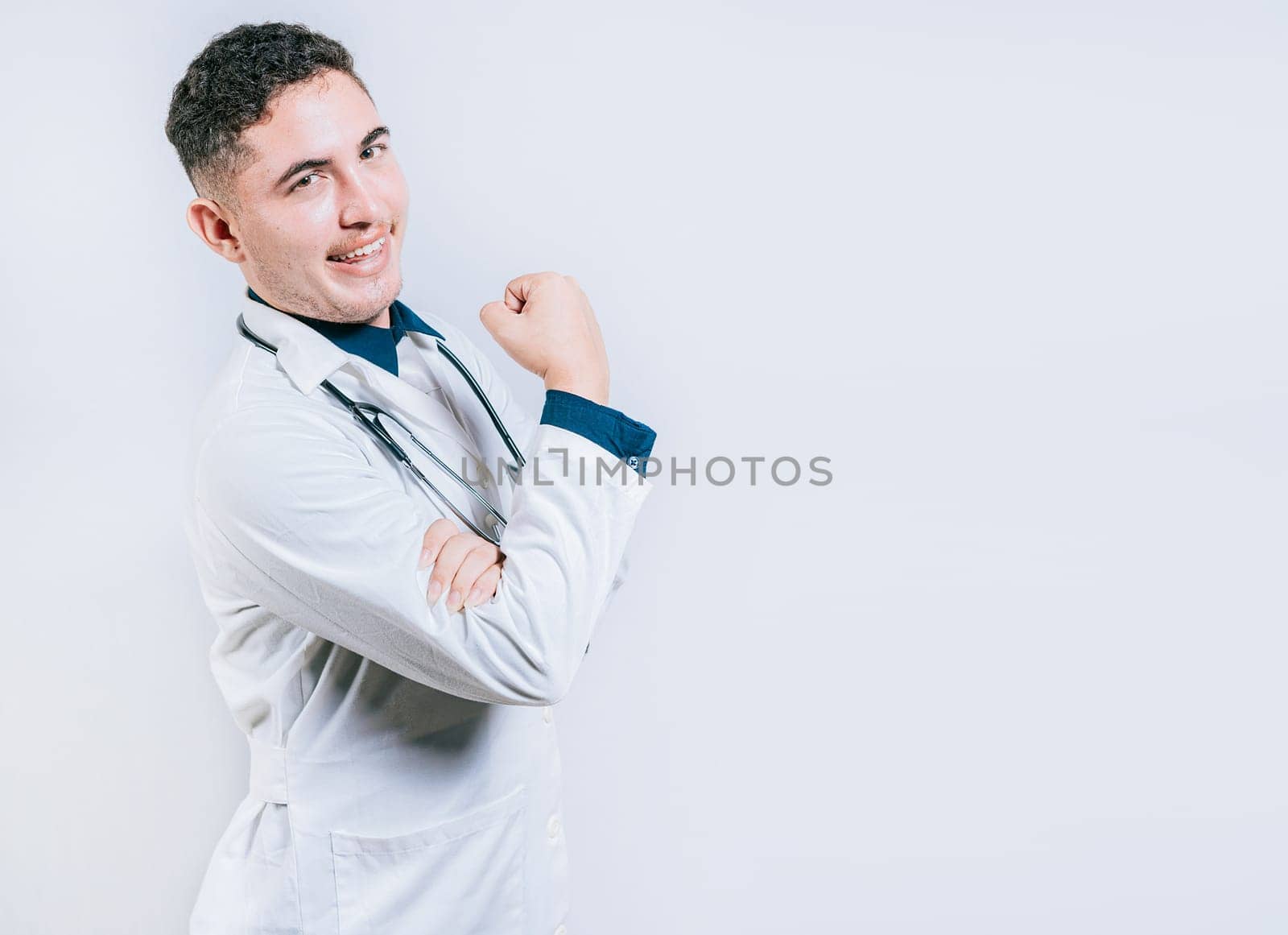 Doctor showing muscle and smiling isolated. Young doctor showing strength with his arm