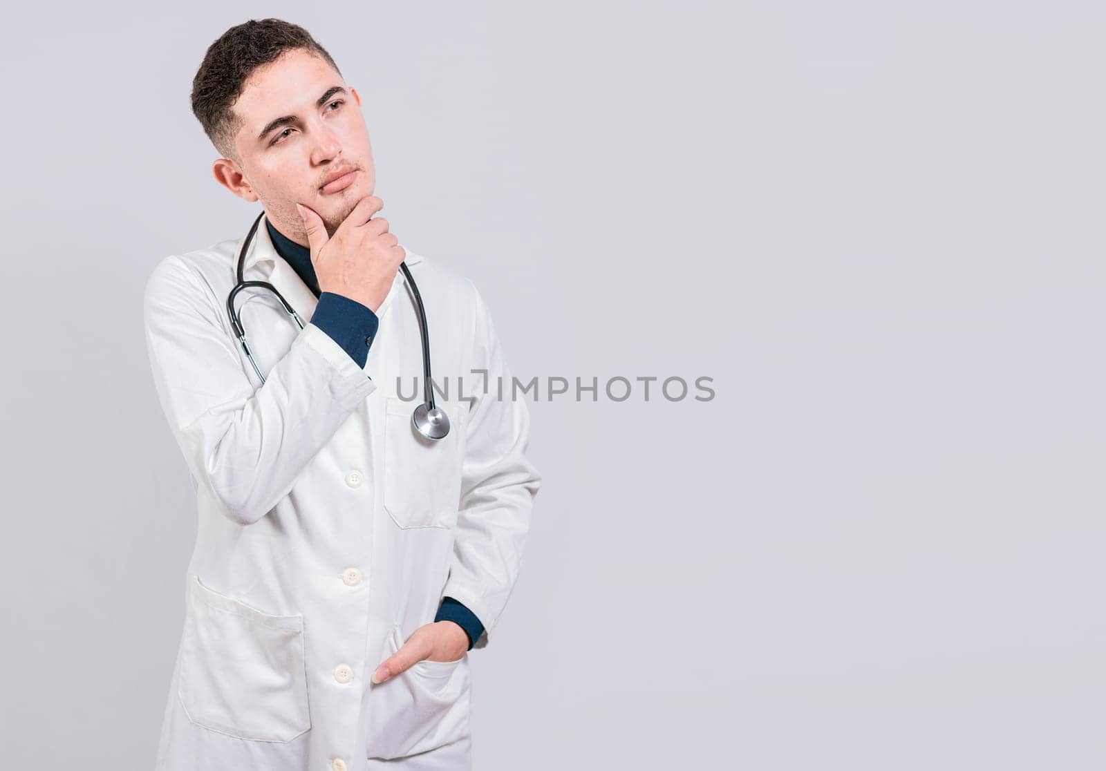 Doctor thinking with hand on chin. Pensive doctor man looking up, Young doctor thinking and looking up isolated