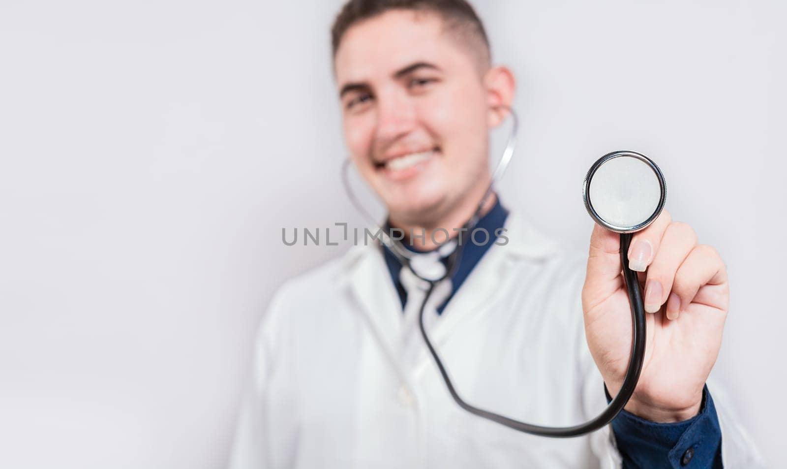 Happy young doctor holding stethoscope looking at camera. Portrait of latin doctor holding stethoscope isolated