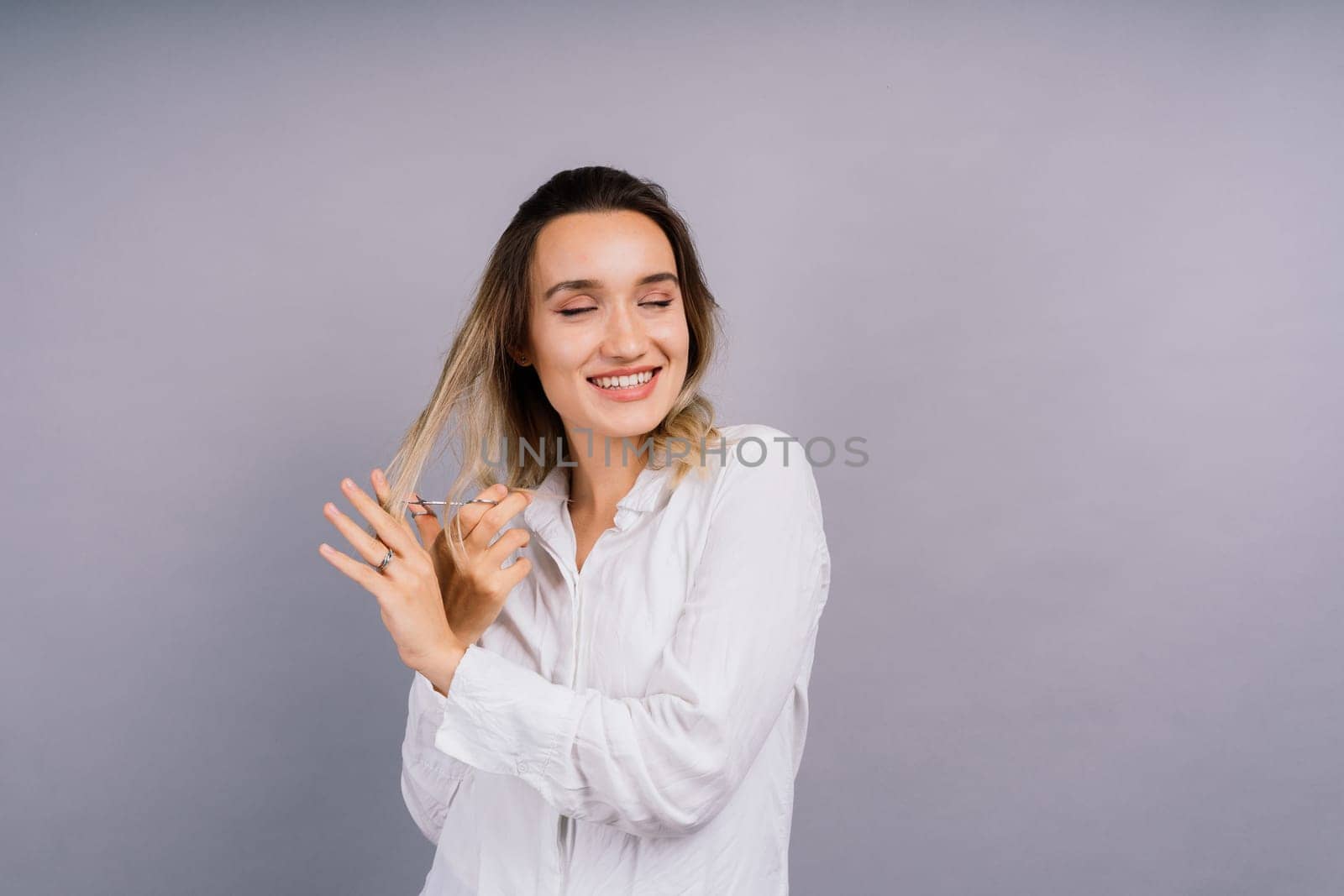 Woman with a scissors having hair cut. Amazed female with straight hair, scissor. Haircare concept.