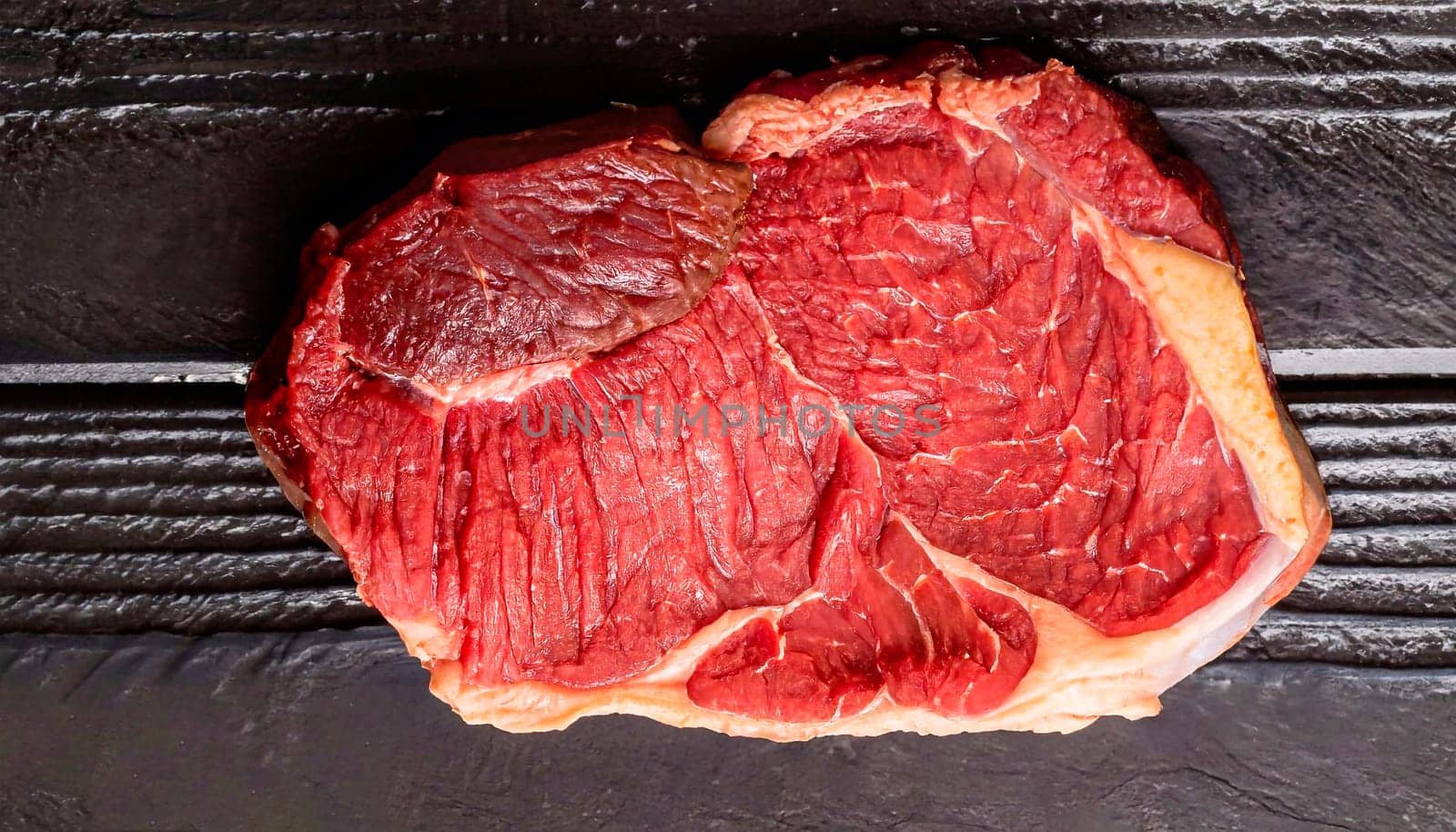 Raw dry aged wagyu cap of rump beef offered as top view on black background with copy space