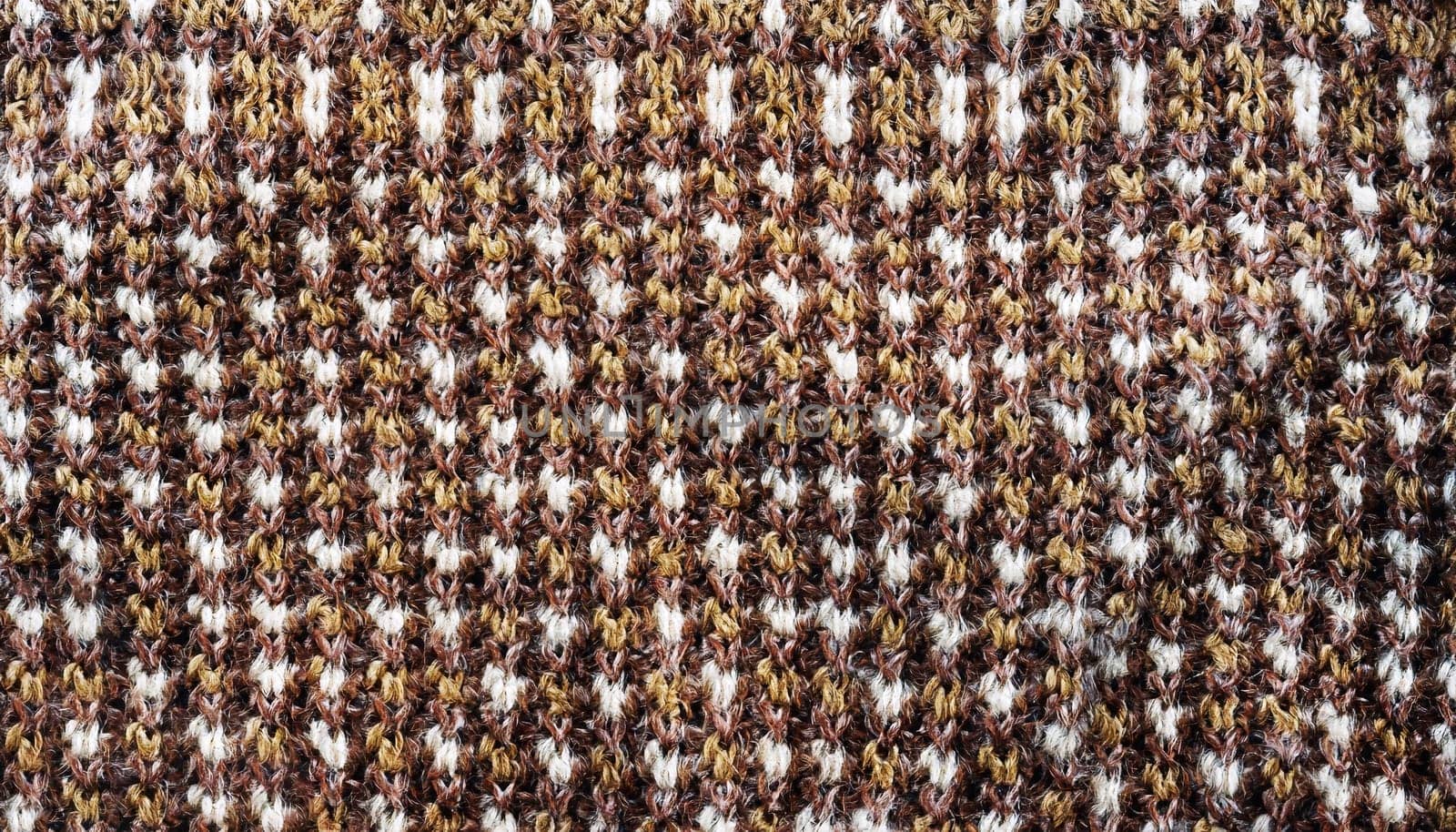 Wool sweater texture of light brown, dark brown and white color with geometric ornament. Natural knitted wool material with decorative ornament. Horizontal background with knitted fabric texture