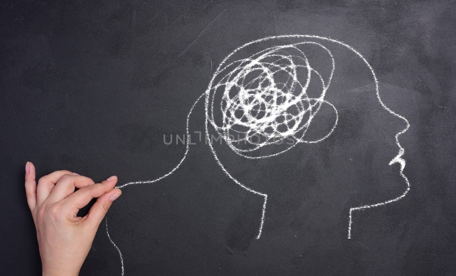 Profile of a human head with a tangled spiral in the brain area. The head is drawn in white chalk. Mental health concept