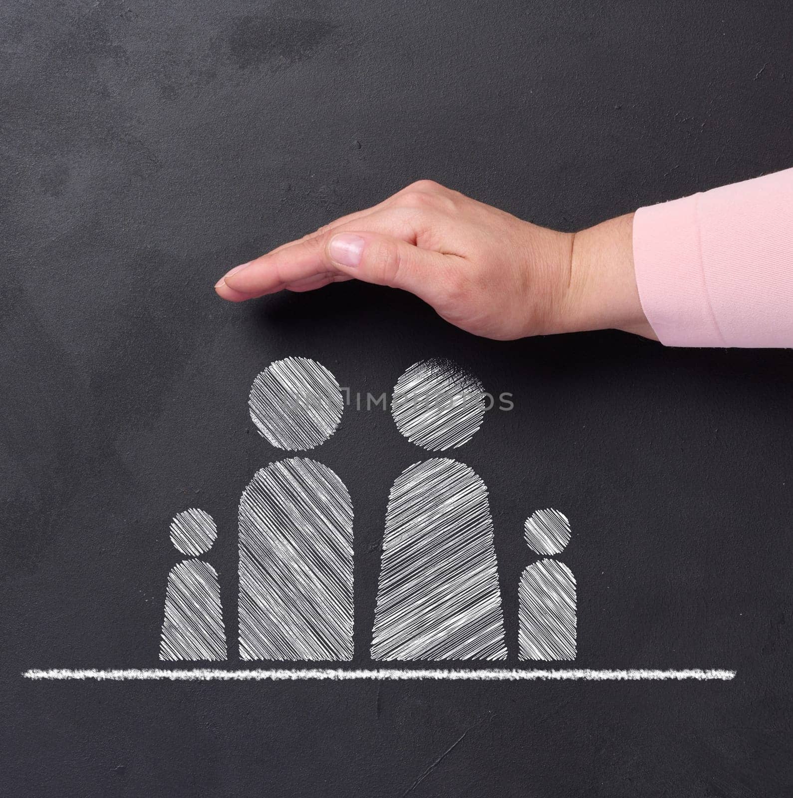 Chalk-drawn family on a blackboard with a hand above, symbolizing the concept of protection, guidance, and support for families