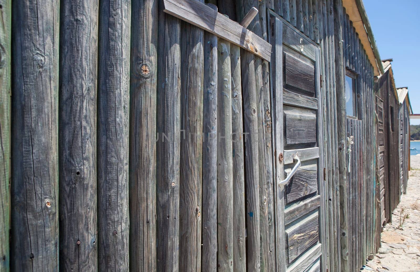Weathered wooden walls built with logs. Dark knotted and faded greyish look