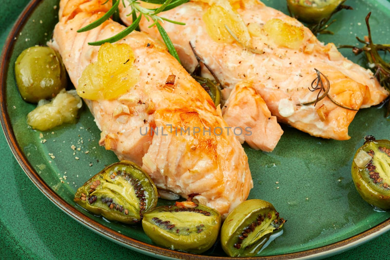 Salmon steaks grilled with mini kiwi on rustic wooden table. Top view.