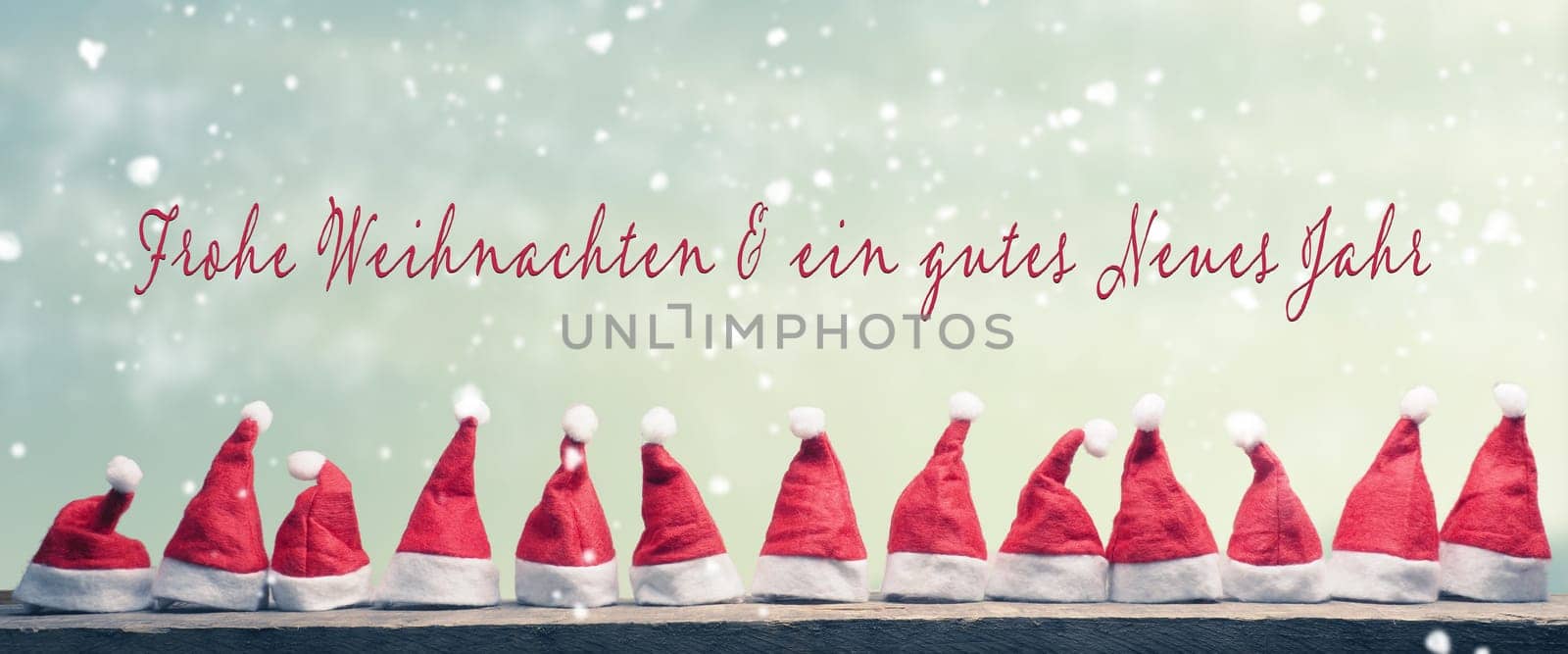 Many hats of Santa in a row on a rustic wooden table with the German words Merry Christmas and a happy New Year, panoramic view