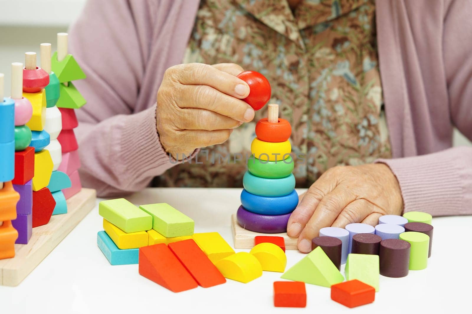 Asian elderly woman playing puzzles game for treatment dementia prevention and Alzheimer disease.