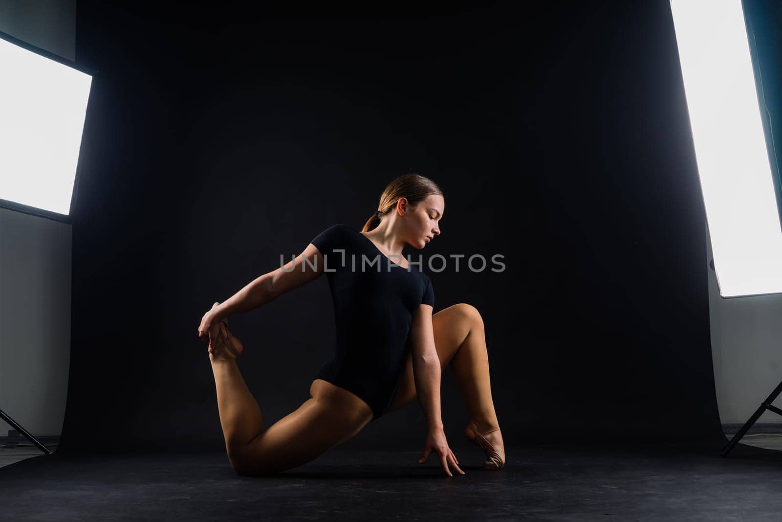 Sportive exercises, standing and stretching the hands. Beautiful muscular woman in indoors studio.