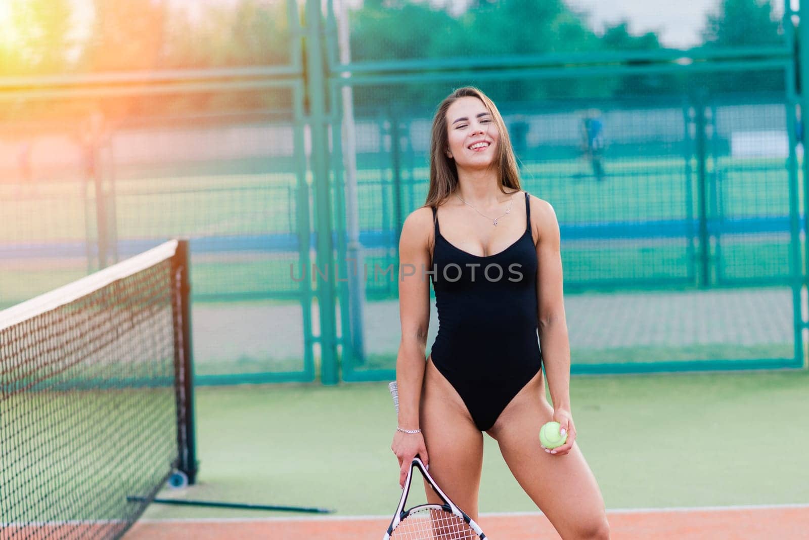 Beautiful young sport female dressed in a bodysuit on tennis court