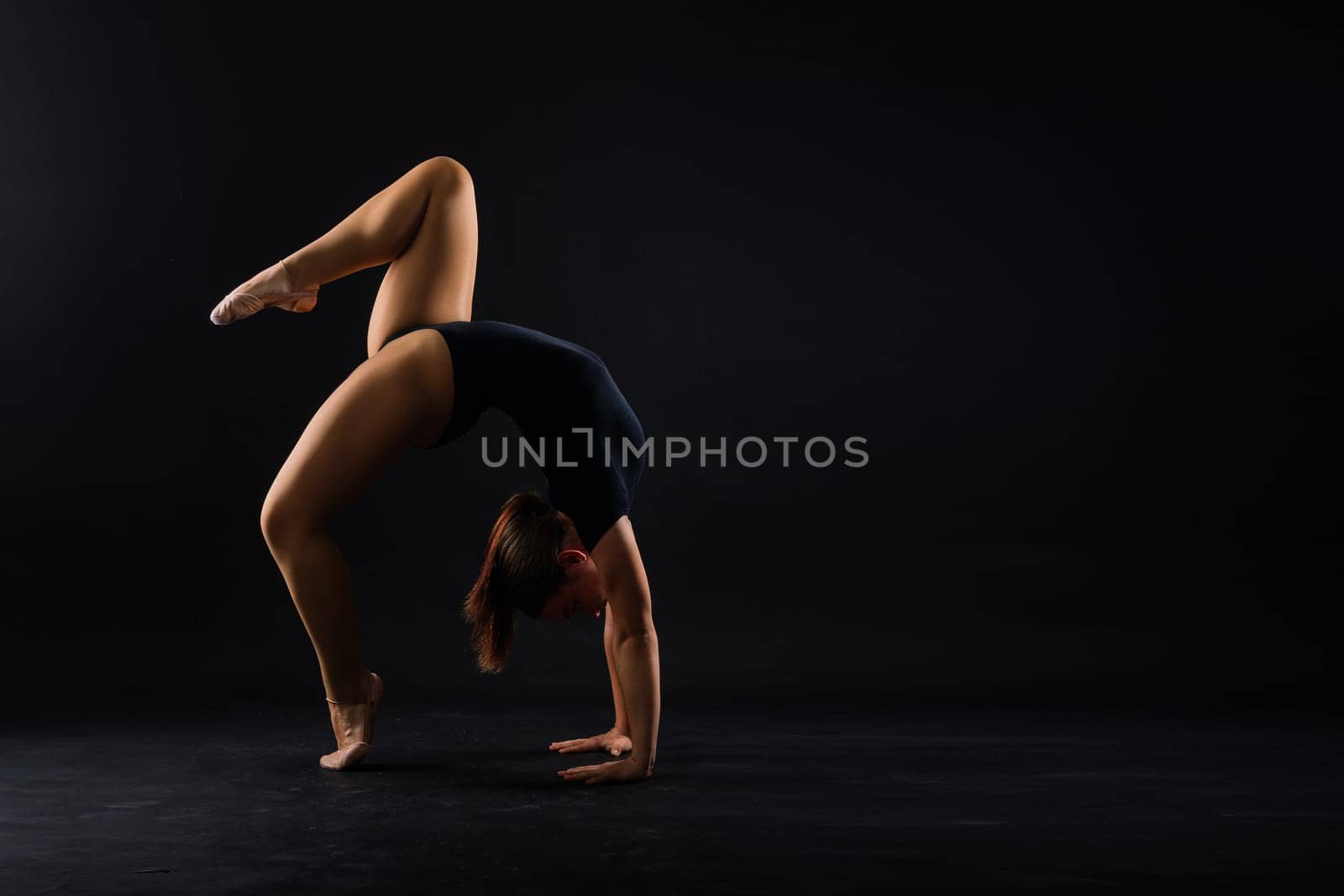 Portrait of a beautiful young woman gymnast training calilisthenics exercise with acrobatic element