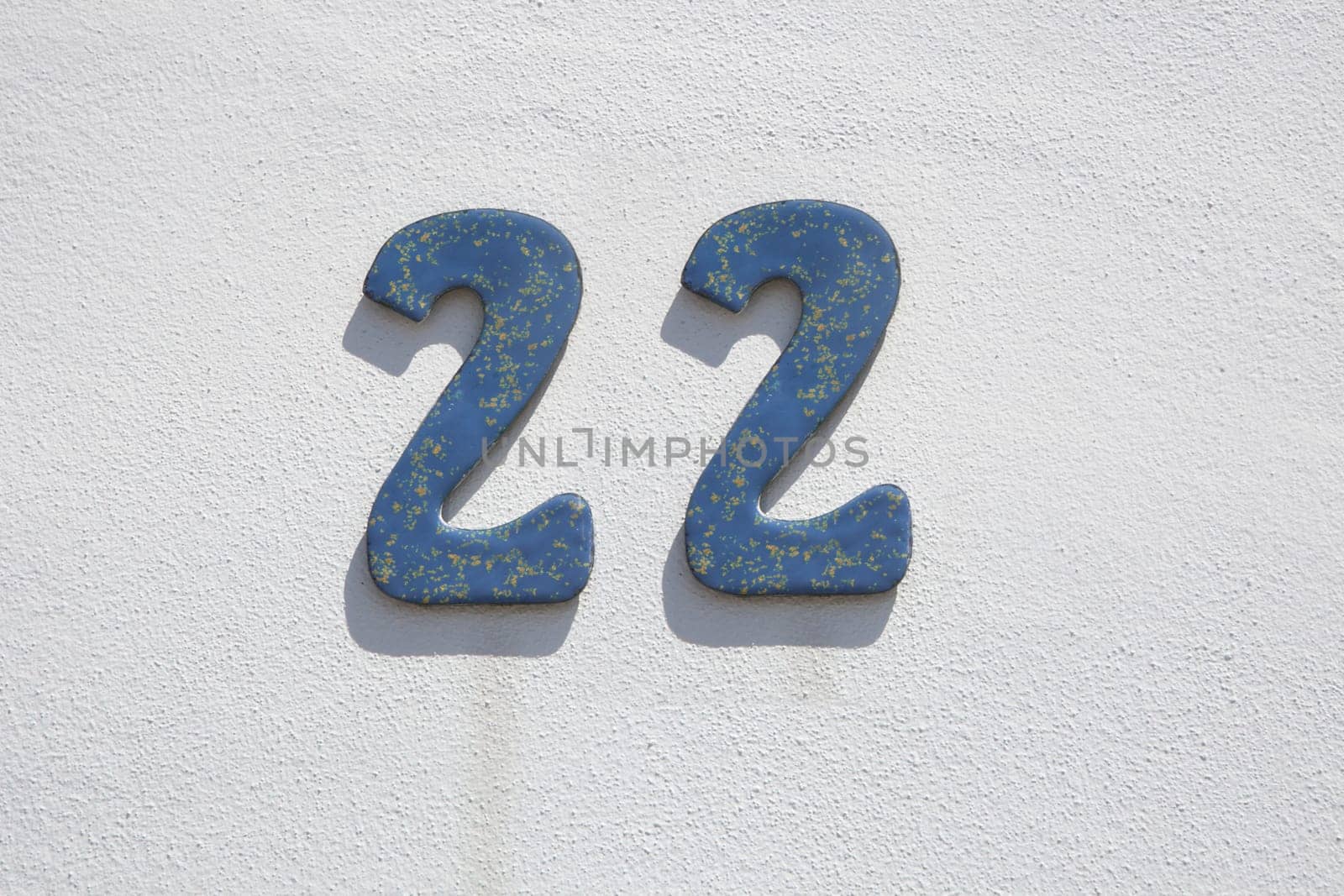 House number 22. Painted iron over whitewashed wall. Houses with personality concept