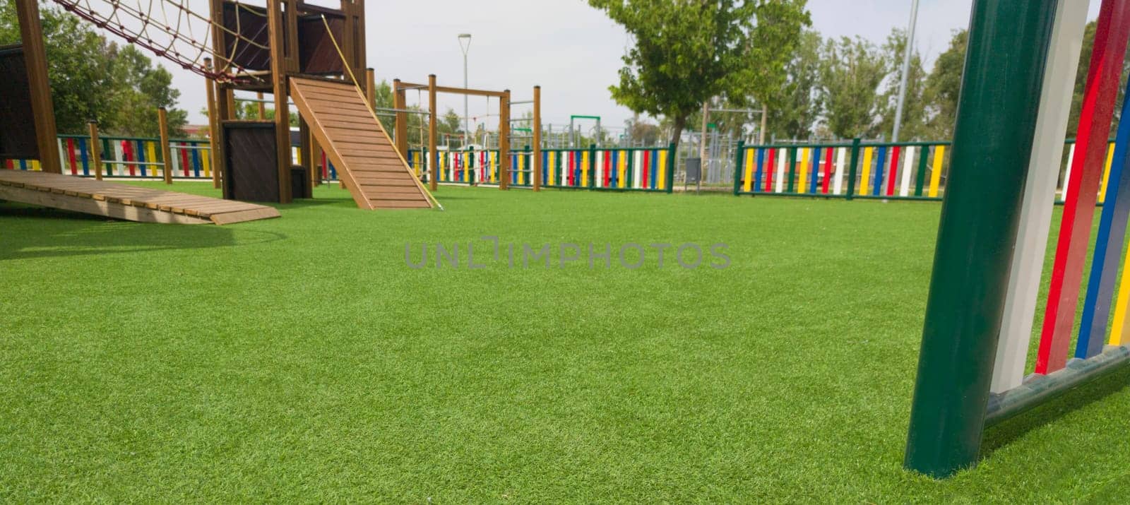 Artificial green grass floor on playground. Colourful rows of painted posts arround